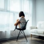 Foto: Frau sitzt alleine auf einem Stuhl mit angezogenen Beinen - Trennung von einem Narzissten