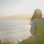 Foto: Rückenansicht einer Frau, die aufs Meer schaut