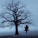 Foto: Baum mit Schaukel, auf der eine Frau Sitzt