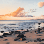 Foto: Frau sitzend am Strand mit Sonnenuntergang