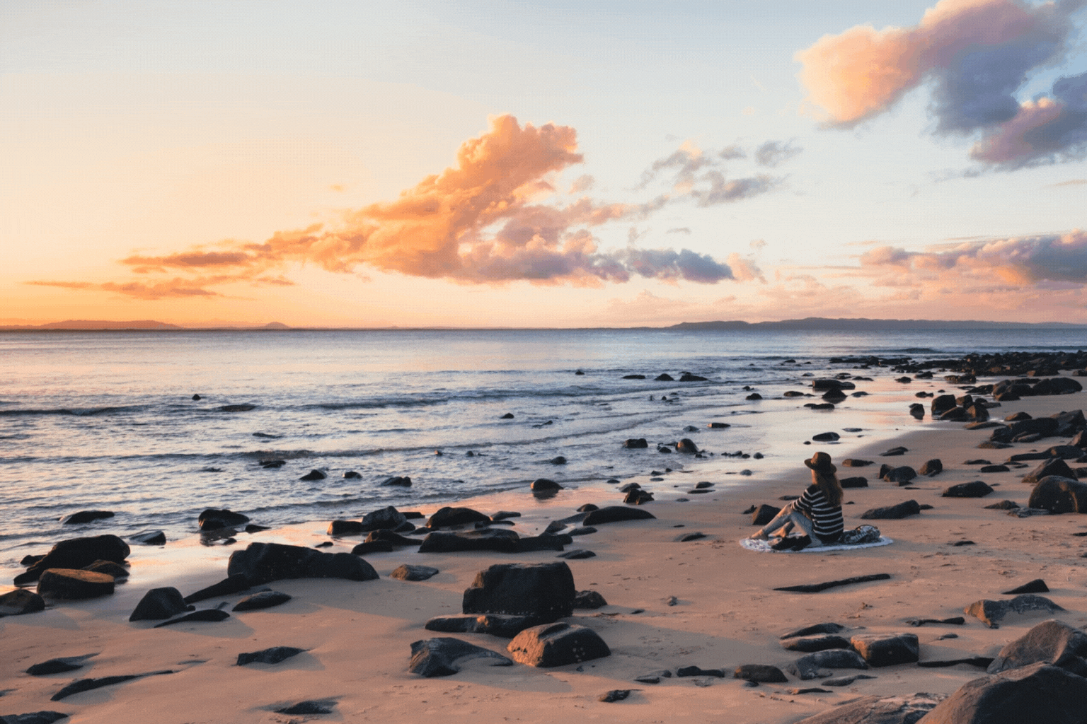 Foto: Frau sitzend am Strand mit Sonnenuntergang