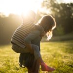 Foto: Mädchen trägt kleineren Jungen Huckepack