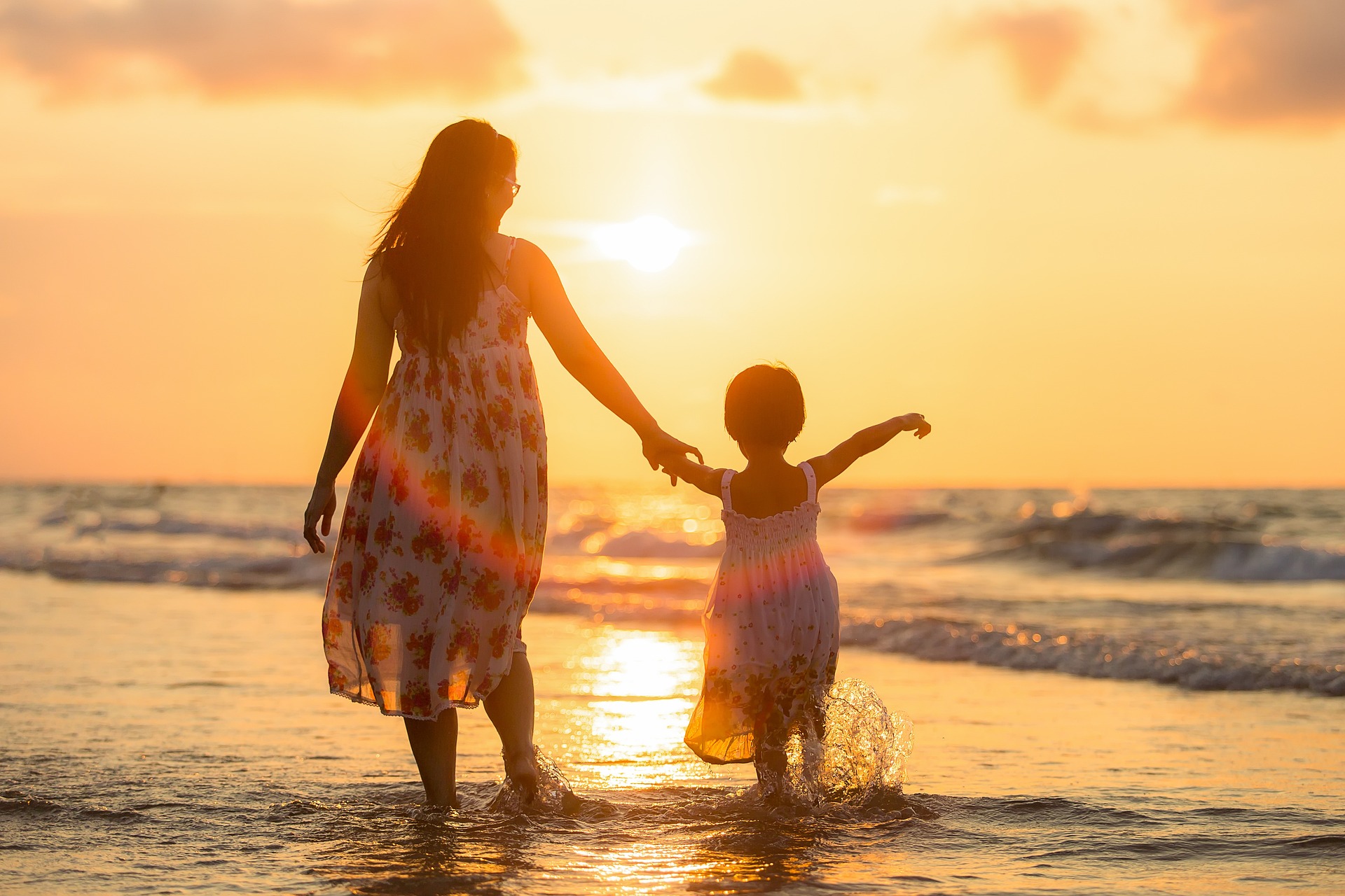 Foto: Szene am Meet mit Sonnenuntergang, Mutter hält Tochter an der Halt