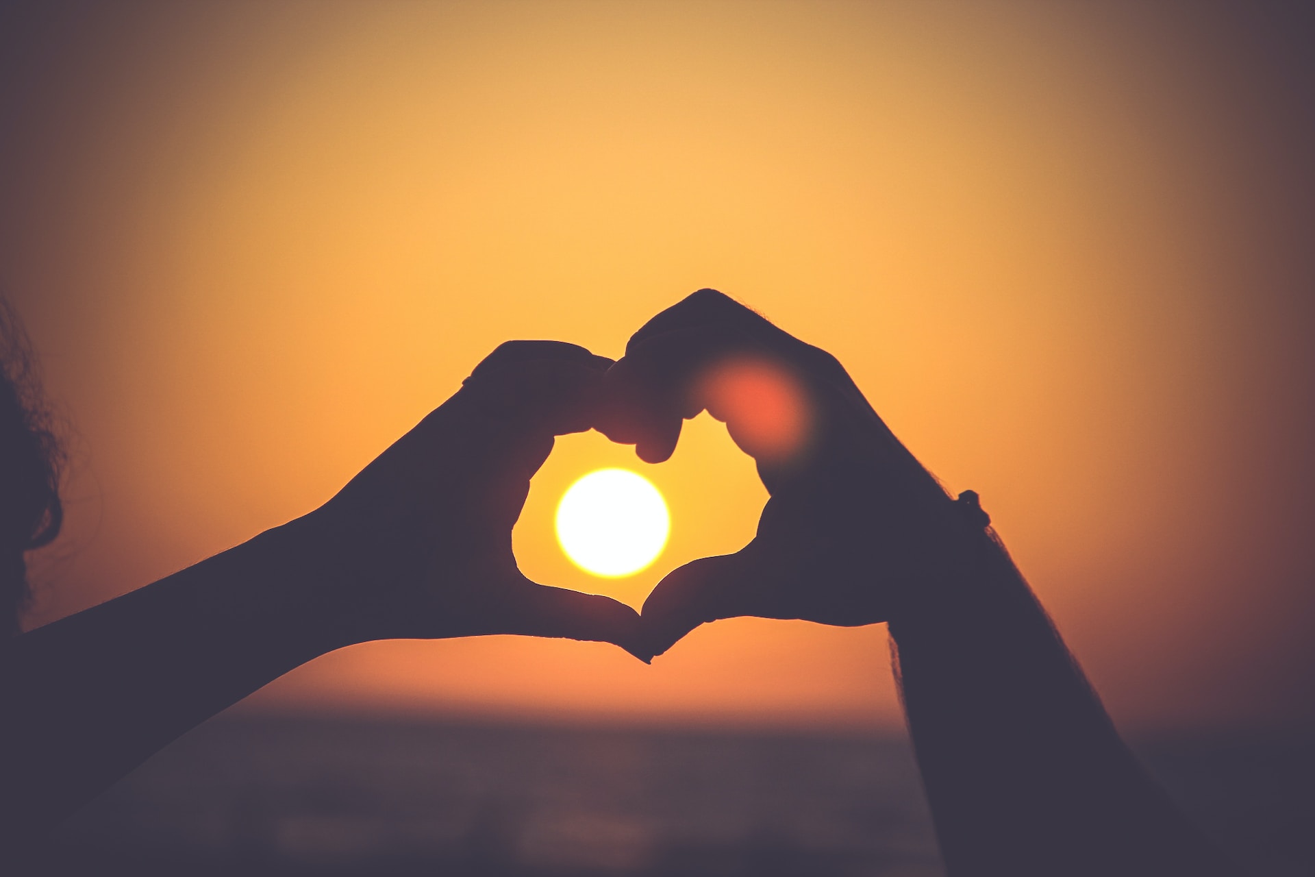 Foto: Hände formen ein Herz im Sonnenuntergang